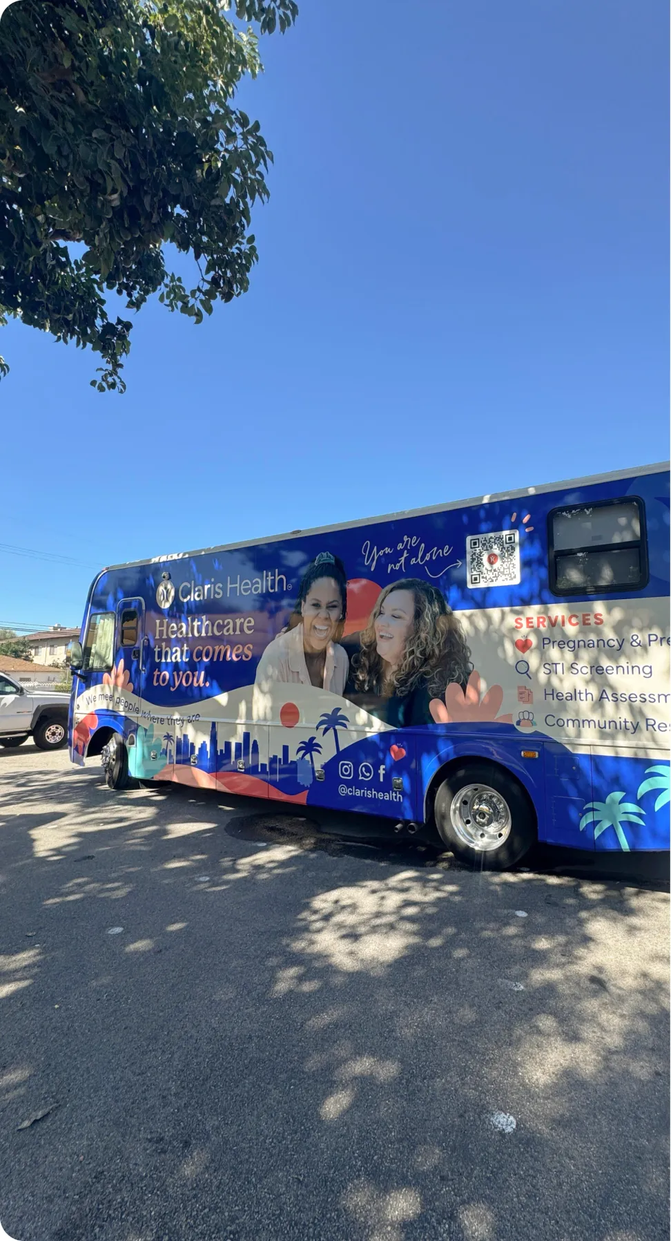 The Claris Health mobile clinic van parked under trees