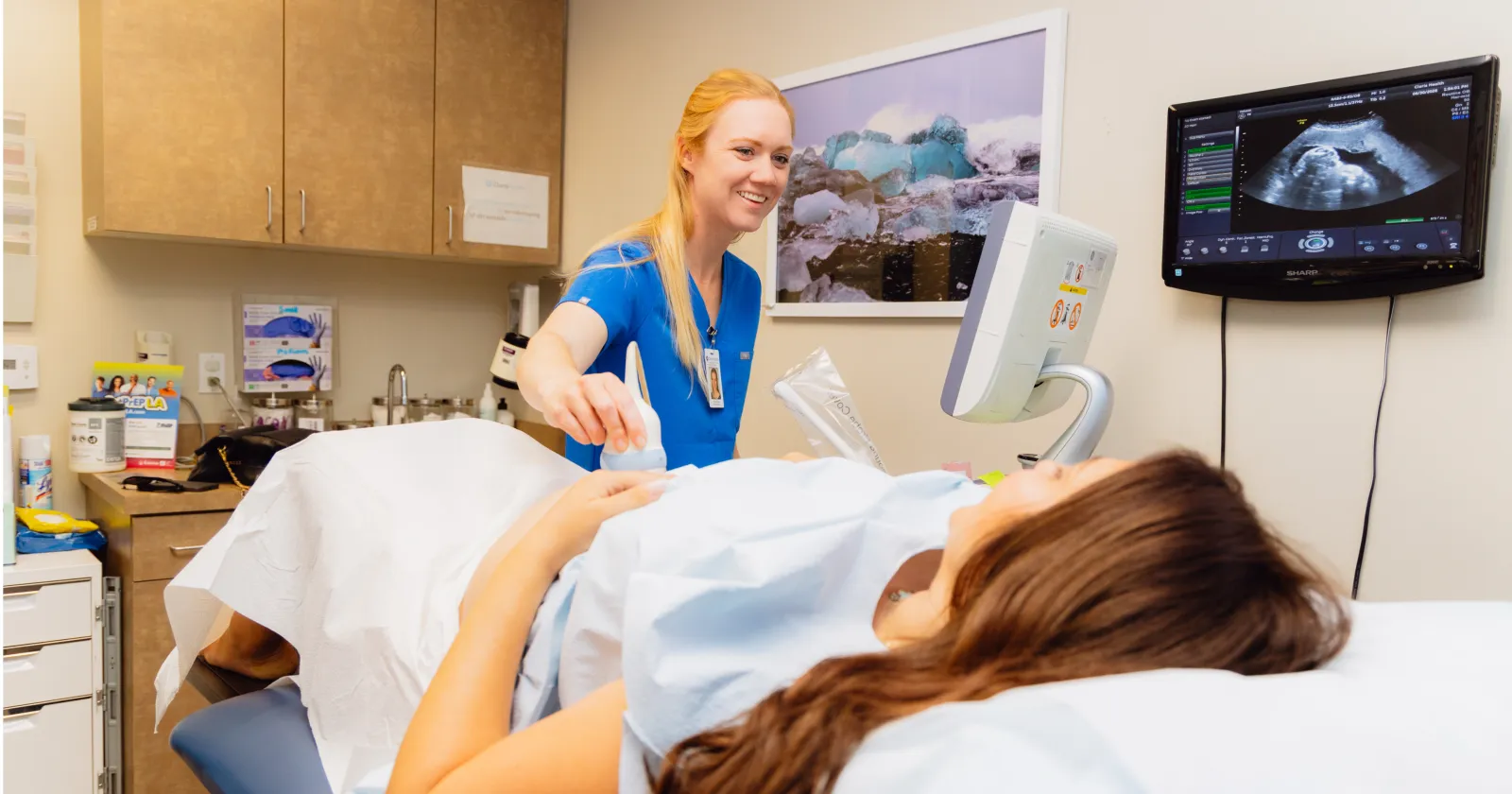 A Claris clinician performing an ultrasound for a patient lying on an exam table